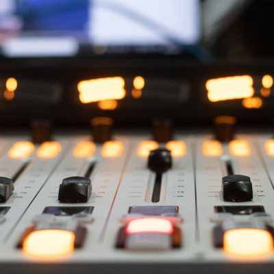 Detailed view of a professional audio mixing console with illuminated sliders and buttons.